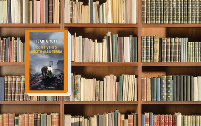 L'immagine mostra la copertina del libro "Come vento cucito alla terra" di Ilaria Tuti bordata di arancione. Sullo sfondo si vede uno scaffale pieno di libri.
