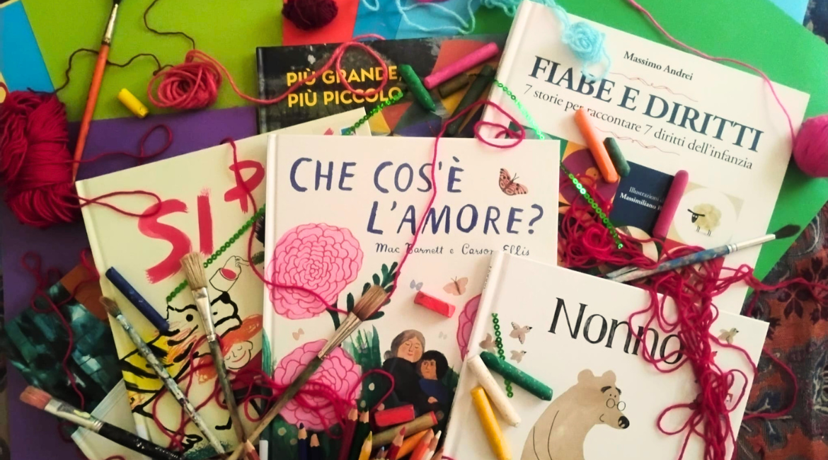 Nell'immagine si vede un tavolo con esposti libri per bambini e pastelli colorati.