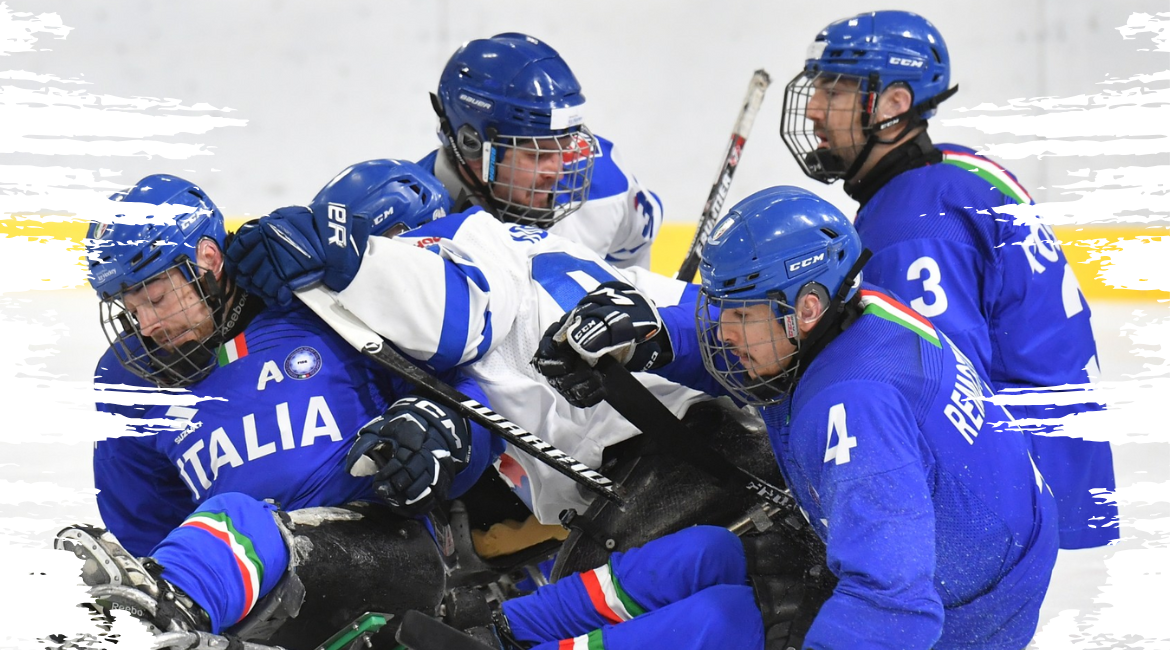 Nella foto si vedono quattro giocatori di Para Ice Hockey ingaggiati in un'azione sul ghiaccio.